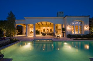 Large pool in the backyard of a contemporary white mansion with covered patio